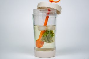 a cup filled with liquid and vegetables inside of it